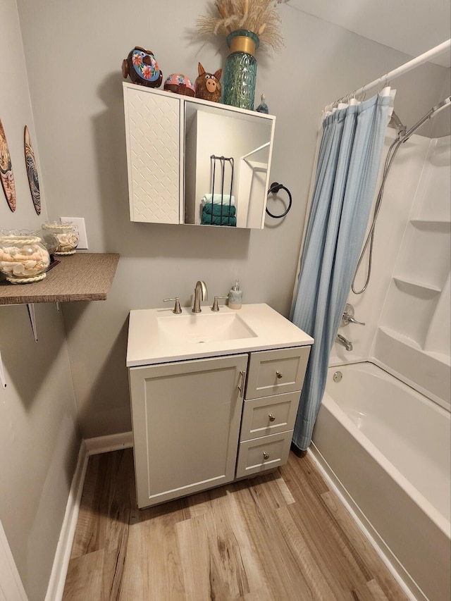 bathroom with wood finished floors, baseboards, shower / bathtub combination with curtain, and vanity