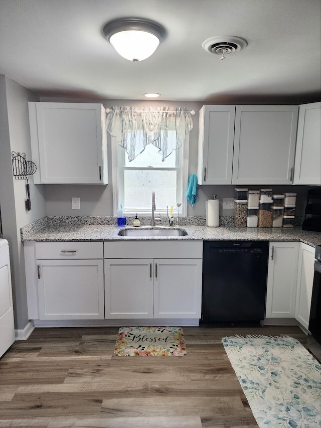 kitchen featuring dishwasher, a sink, white cabinets, light stone counters, and wood finished floors
