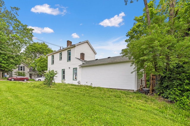 rear view of property with a chimney and a yard