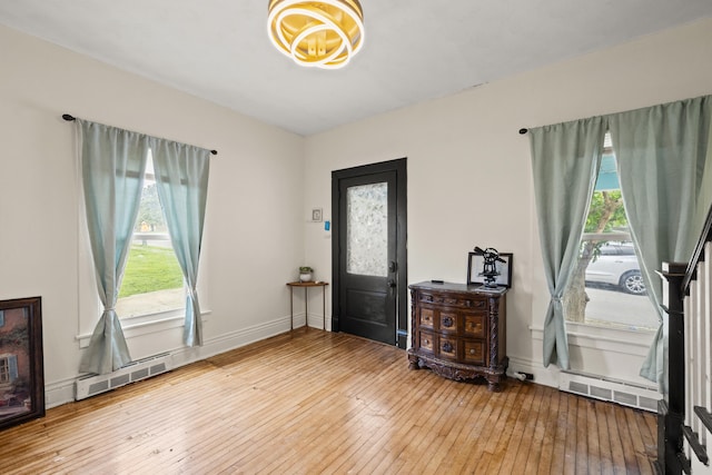 entrance foyer with healthy amount of natural light, wood-type flooring, and a chandelier
