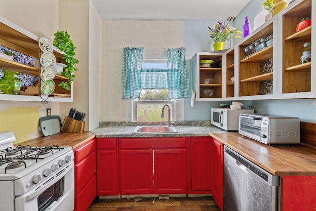 kitchen with white appliances, a sink, butcher block countertops, red cabinetry, and dark wood-style floors