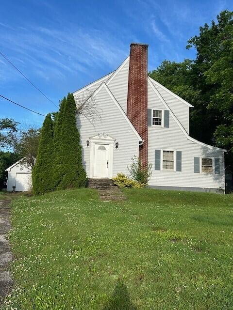 view of property exterior with a chimney, a yard, and a garage