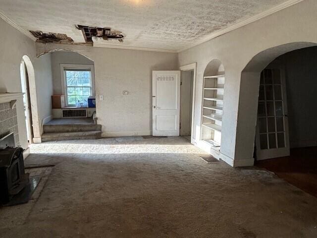 unfurnished living room with built in shelves, carpet, crown molding, and baseboards