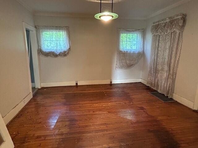 unfurnished dining area with ornamental molding, hardwood / wood-style floors, and baseboards