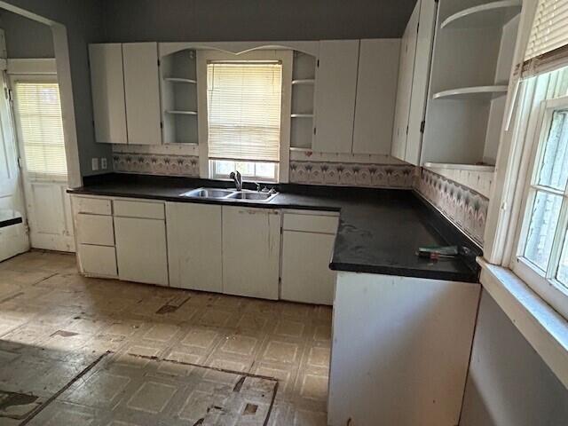 kitchen featuring open shelves, a sink, dark countertops, and tasteful backsplash