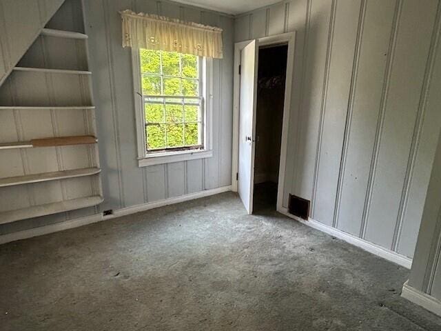 unfurnished bedroom with carpet flooring and a decorative wall