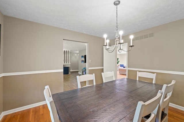 3540 Cornwall Dr, Lexington, KY 40503 - dining room with a chandelier, a textured ceiling, wood finished floors, and baseboards
