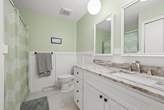 3540 Cornwall Dr, Lexington, KY 40503 - bathroom featuring vanity, toilet, wainscoting, tile patterned flooring, and a decorative wall