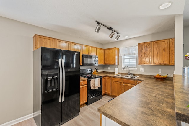 kitchen with black appliances, a sink, dark countertops, and brown cabinetry