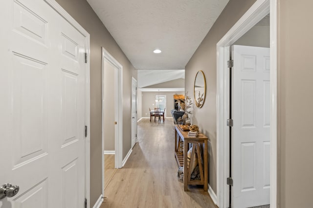 hallway featuring light wood-style floors, baseboards, and recessed lighting