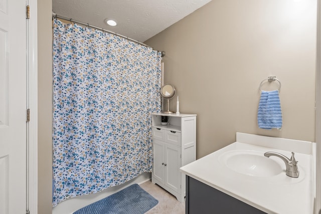 full bath featuring vanity, curtained shower, and a textured ceiling