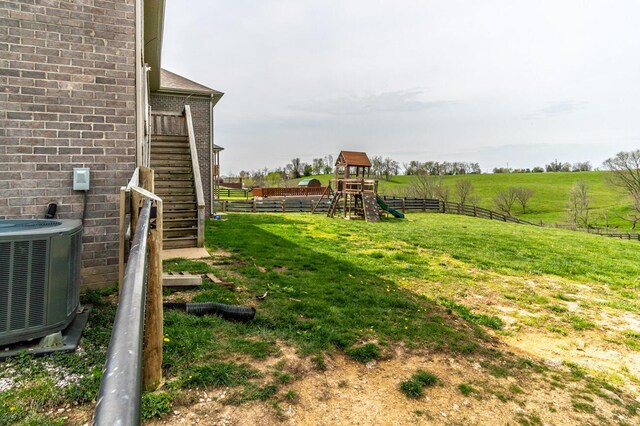 view of yard featuring central AC unit, a playground, stairway, and a rural view