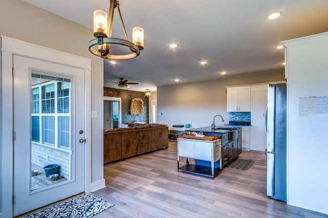 kitchen featuring freestanding refrigerator, white cabinetry, open floor plan, a chandelier, and a ceiling fan
