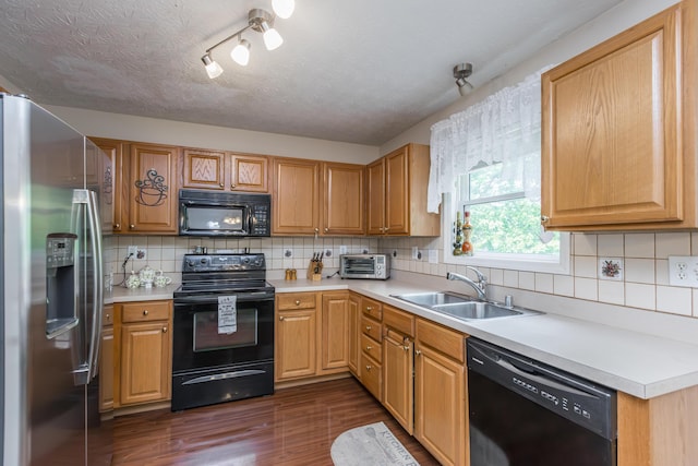 kitchen featuring black appliances, a sink, dark wood-style floors, light countertops, and backsplash