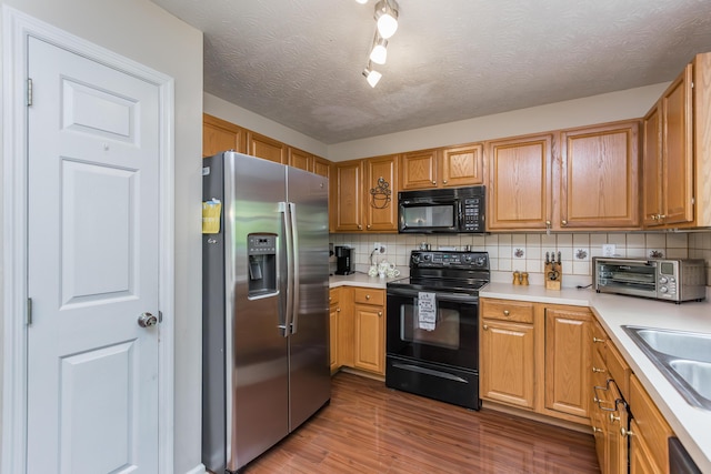 kitchen with black appliances, decorative backsplash, dark wood-style flooring, light countertops, and a textured ceiling