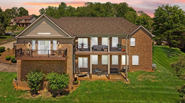 43 Enclave Dr, Somerset, KY 42503 - back of house at dusk with a balcony, a patio, a lawn, and brick siding