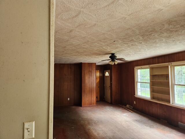 empty room with wood walls and ceiling fan