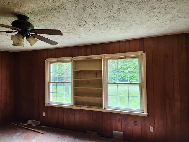 empty room with wood walls and ceiling fan