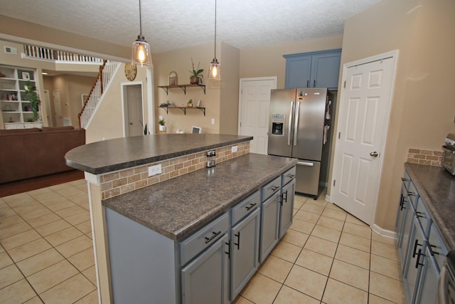 2812 Jenna Rst, Lexington, KY 40511 - kitchen featuring stainless steel refrigerator with ice dispenser, dark countertops, a kitchen island, light tile patterned floors, and a textured ceiling