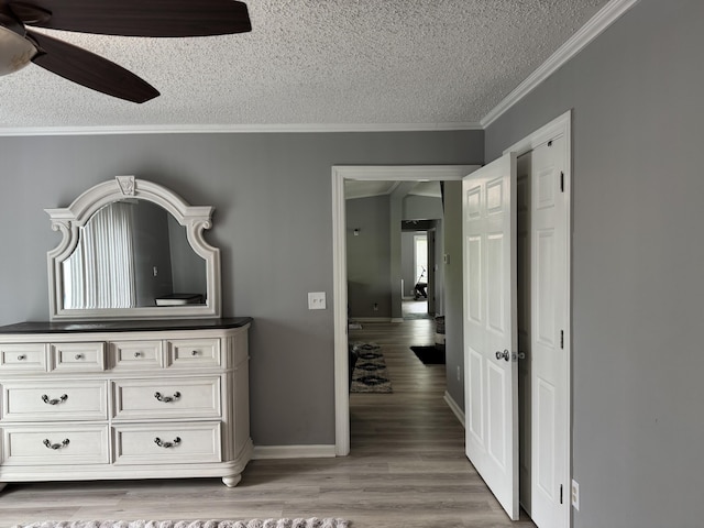 bedroom with a textured ceiling, crown molding, light wood-style flooring, baseboards, and a ceiling fan