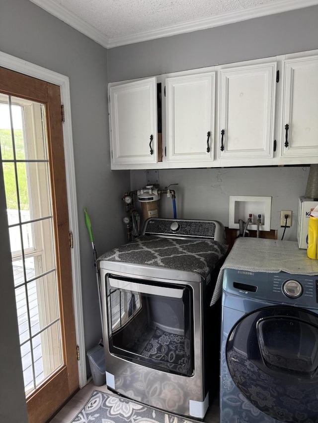 washroom featuring cabinet space, washer and clothes dryer, and ornamental molding