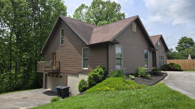 73 Redwood Ln, East Bernstadt, KY 40729 - view of property exterior featuring driveway, a shingled roof, a garage, and fence