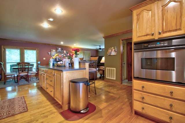 73 Redwood Ln, East Bernstadt, KY 40729 - kitchen featuring stainless steel oven, dark countertops, light wood-style floors, ornamental molding, and a kitchen island
