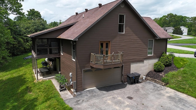 73 Redwood Ln, East Bernstadt, KY 40729 - rear view of property with driveway, a garage, a lawn, a sunroom, and roof with shingles