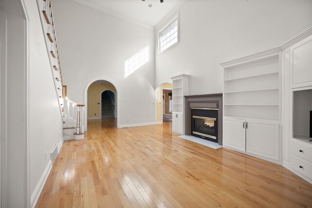 187 Woodside Dr, Somerset, KY 42503 - unfurnished living room with arched walkways, light wood-style floors, ornamental molding, built in shelves, and stairs