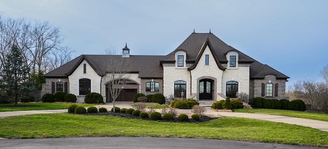 french country home with a front yard, stone siding, and brick siding