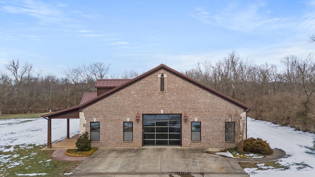 view of snow covered exterior featuring brick siding and metal roof