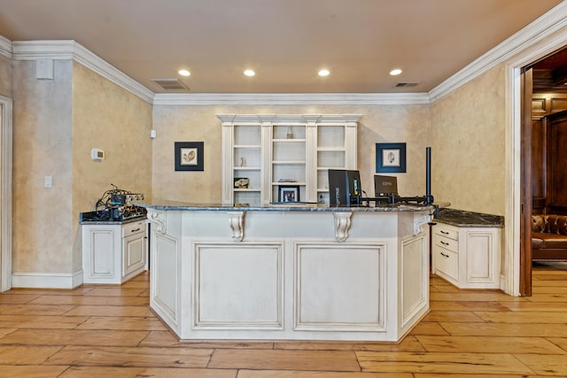 kitchen featuring light wood-style flooring, ornamental molding, dark stone counters, an office area, and open shelves