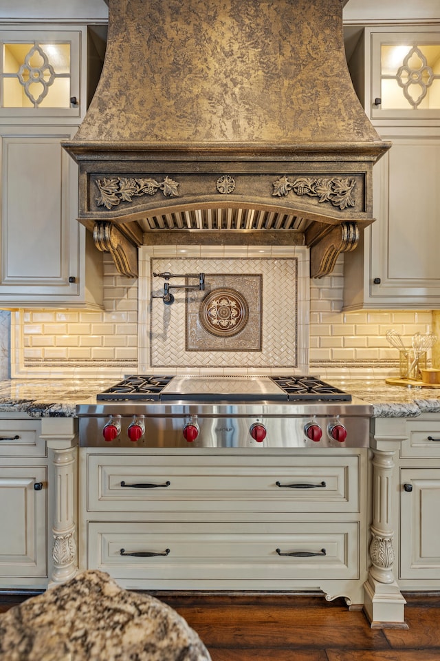 kitchen with stainless steel gas stovetop, glass insert cabinets, and decorative backsplash