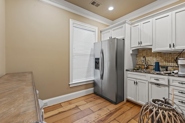 kitchen featuring stainless steel fridge with ice dispenser, a sink, crown molding, light wood-type flooring, and decorative backsplash