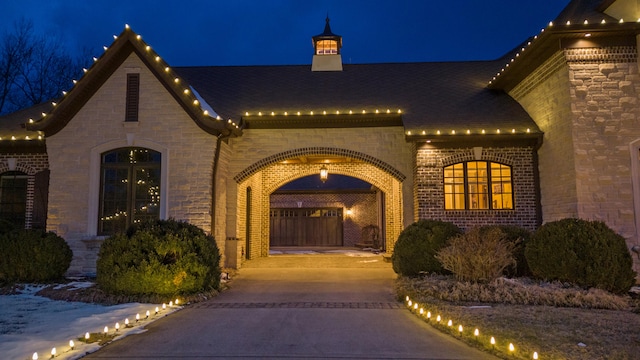 exterior entry at night featuring brick siding and stone siding