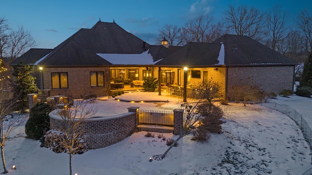 snow covered property with brick siding and a chimney