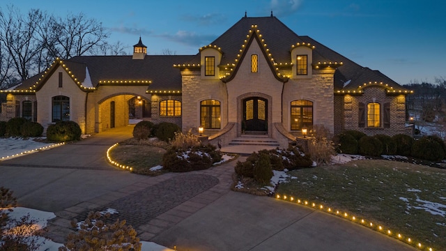 view of front of house with curved driveway, stone siding, and brick siding