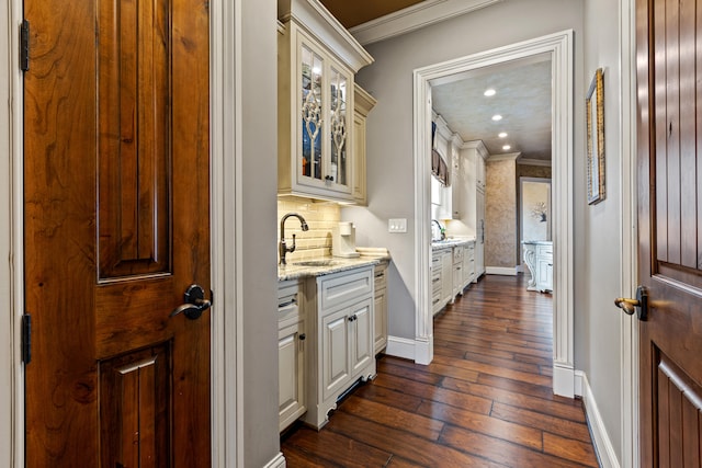 corridor with crown molding, a sink, dark wood finished floors, baseboards, and recessed lighting