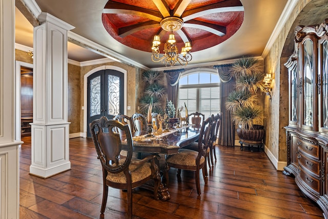 dining area with a raised ceiling, a chandelier, dark wood-type flooring, decorative columns, and crown molding