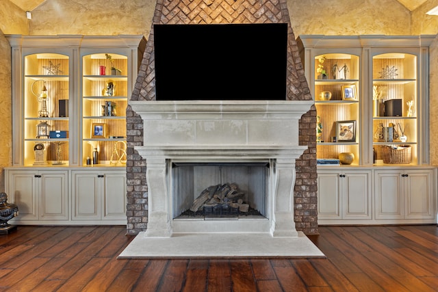 detailed view of a large fireplace, wood finished floors, and built in features