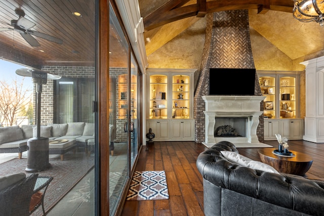 living area featuring hardwood / wood-style floors, ceiling fan, high vaulted ceiling, a fireplace with raised hearth, and built in features