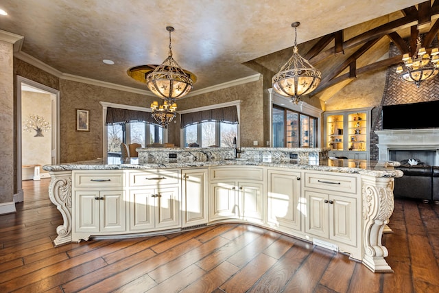 kitchen with a chandelier, cream cabinets, open floor plan, dark wood-style flooring, and vaulted ceiling