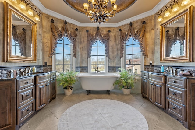 bathroom featuring a chandelier, plenty of natural light, vanity, a soaking tub, and crown molding