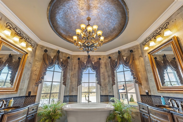 bathroom with a chandelier, vanity, a freestanding tub, crown molding, and tasteful backsplash