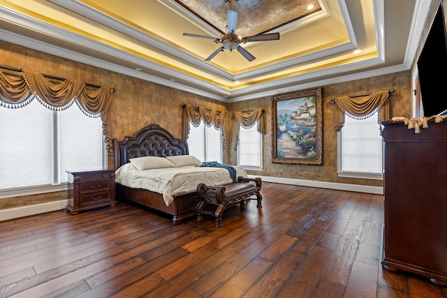 bedroom featuring a tray ceiling, dark wood-type flooring, ornamental molding, baseboards, and a ceiling fan