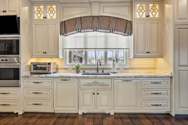kitchen featuring oven, a sink, built in microwave, and cream cabinets