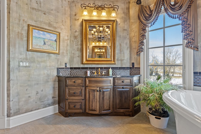 bathroom with a soaking tub, vanity, tasteful backsplash, a chandelier, and baseboards