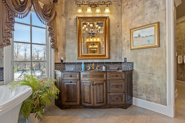 full bathroom with a soaking tub, vanity, baseboards, a chandelier, and tile patterned flooring