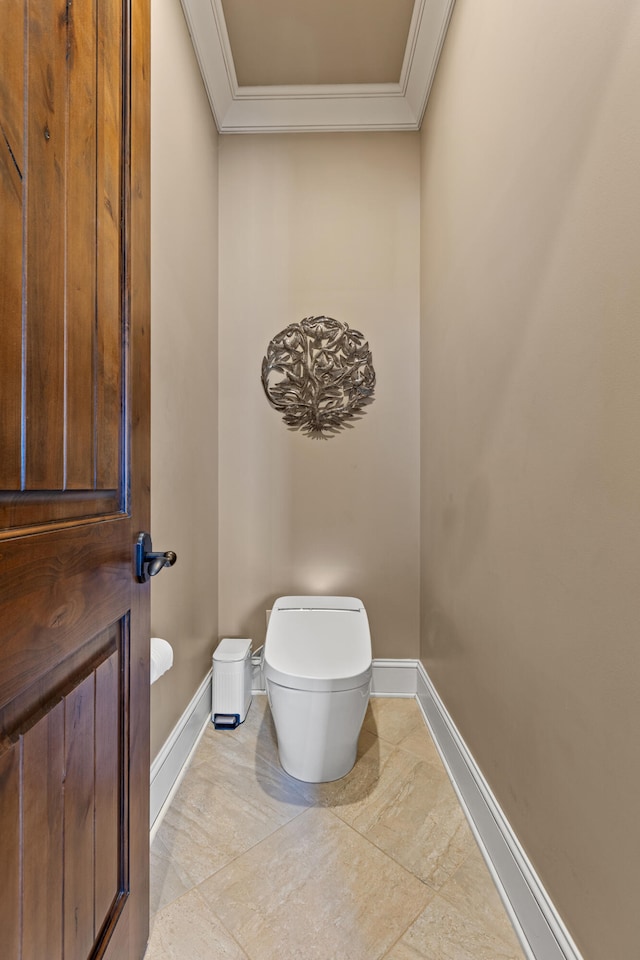 bathroom featuring ornamental molding, baseboards, and toilet