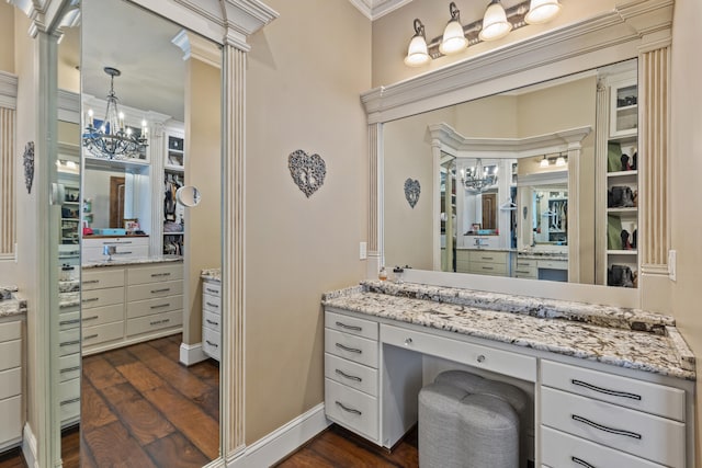 bathroom featuring wood finished floors, vanity, ornamental molding, ornate columns, and a chandelier